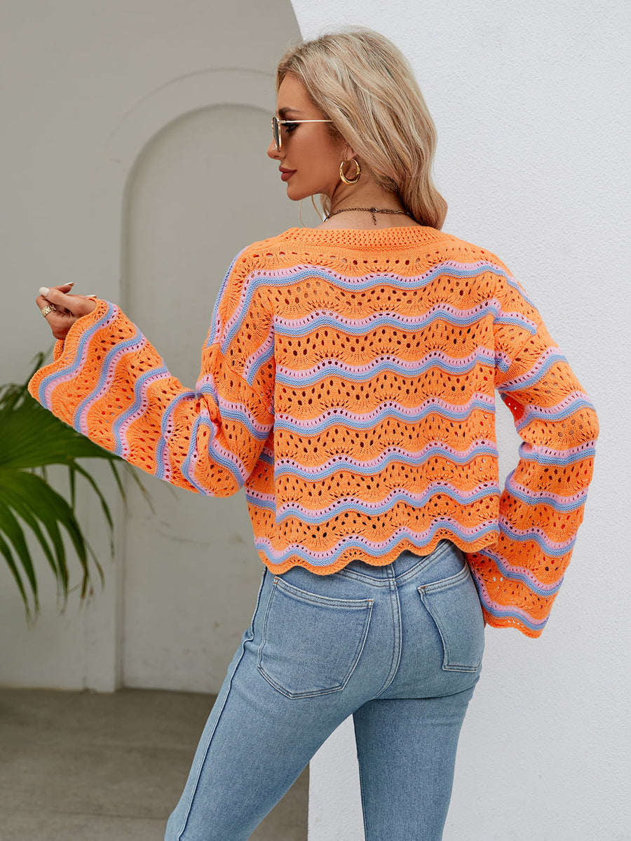 Orange-red crochet crop sweater with blue wave pattern and scalloped hem.