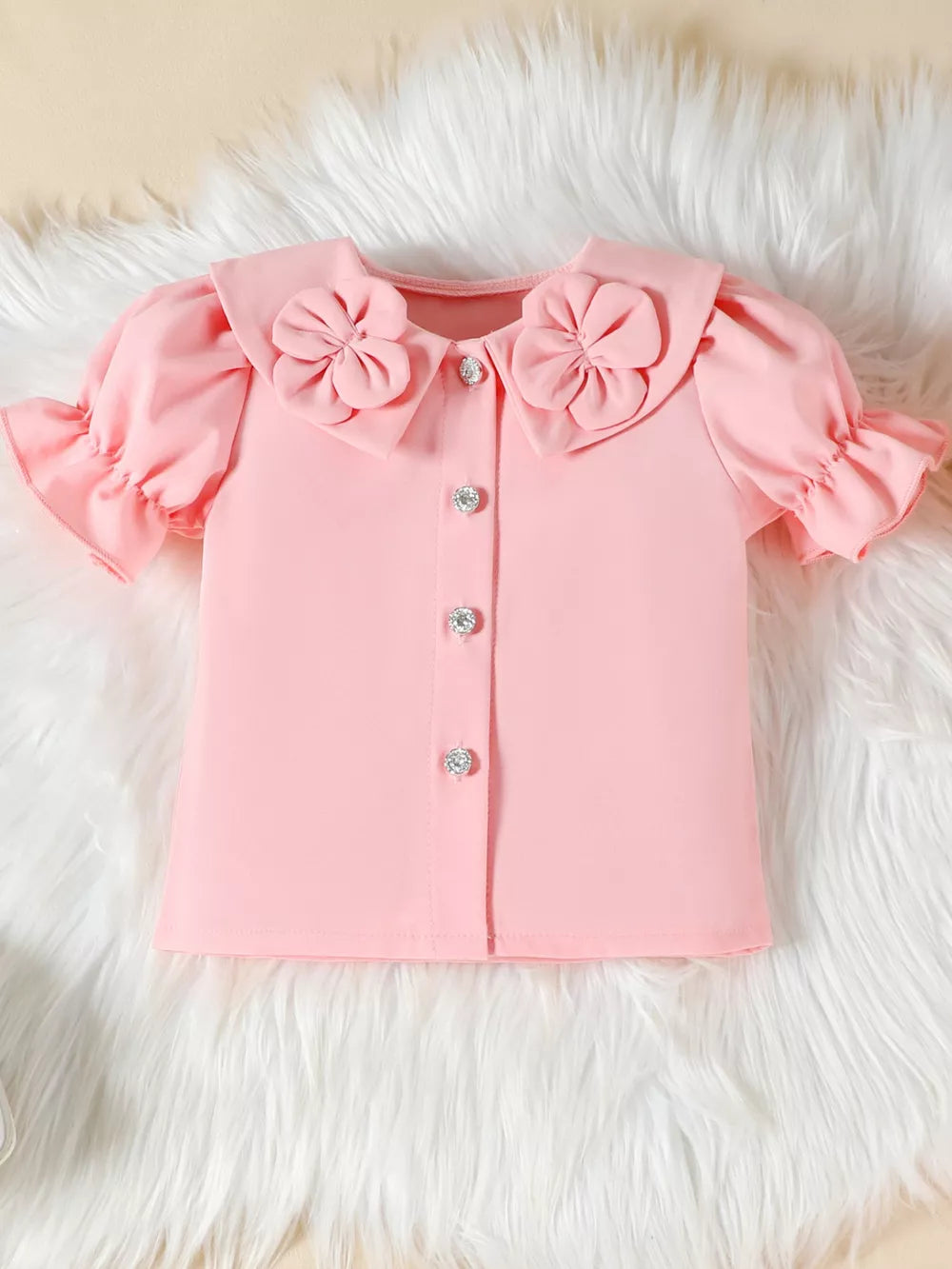 Pink toddler blouse with floral collar, ruffle sleeves, and jeweled buttons.