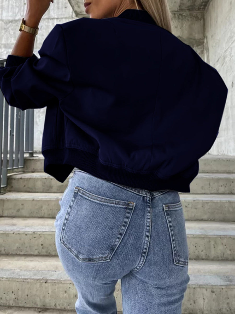 Navy faux leather bomber jacket with elastic cuffs and hem, styled with jeans.