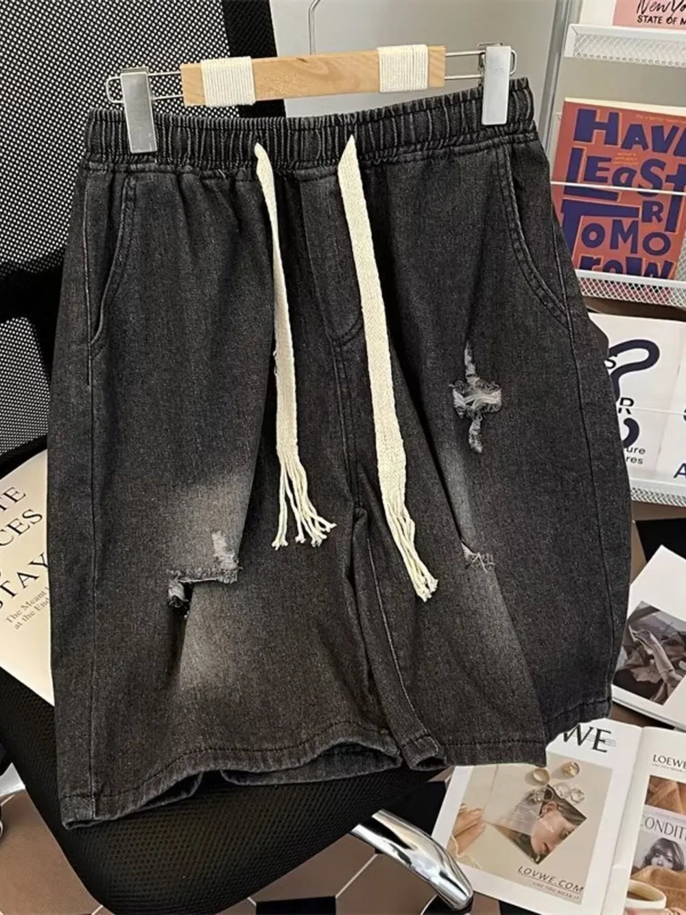 Black distressed denim shorts for men with drawstring waist and frayed details.