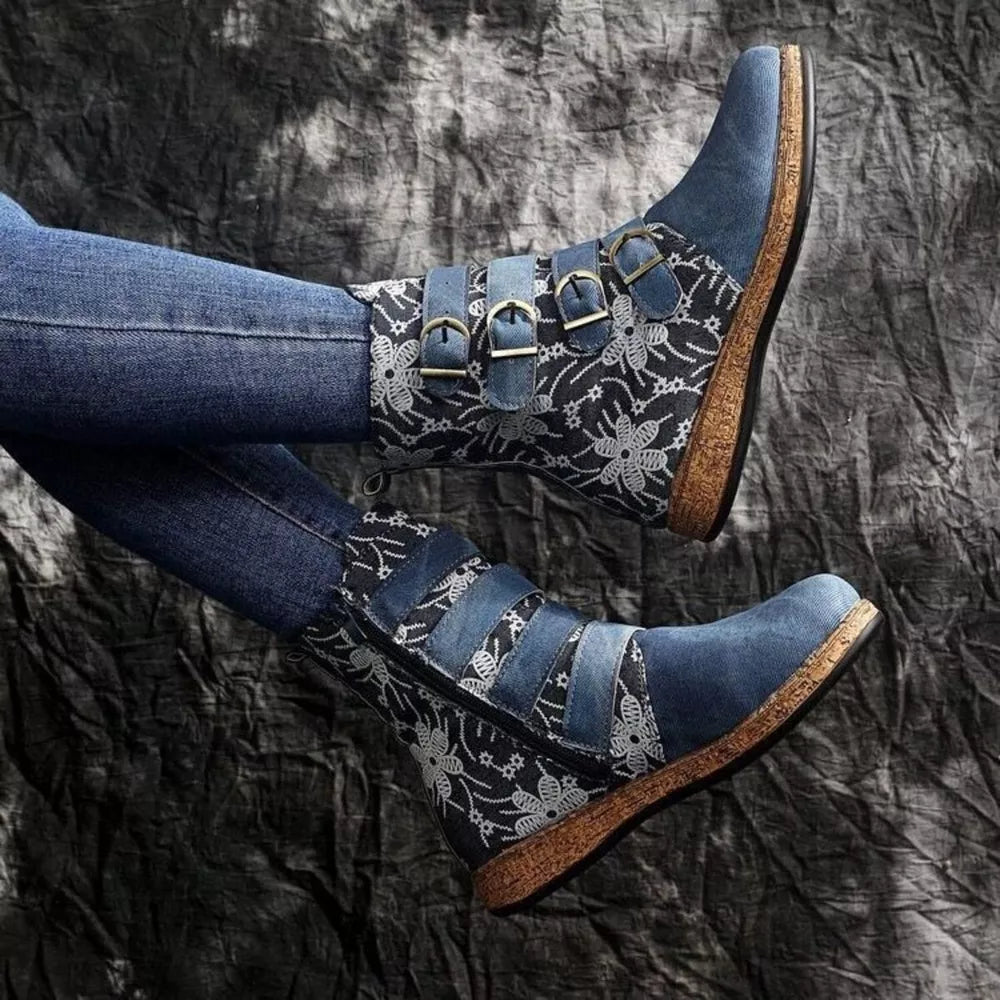 Blue suede ankle boots with floral embroidery and decorative buckle straps.