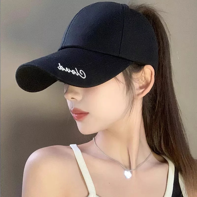 Black baseball cap with white embroidered script logo, ponytail opening