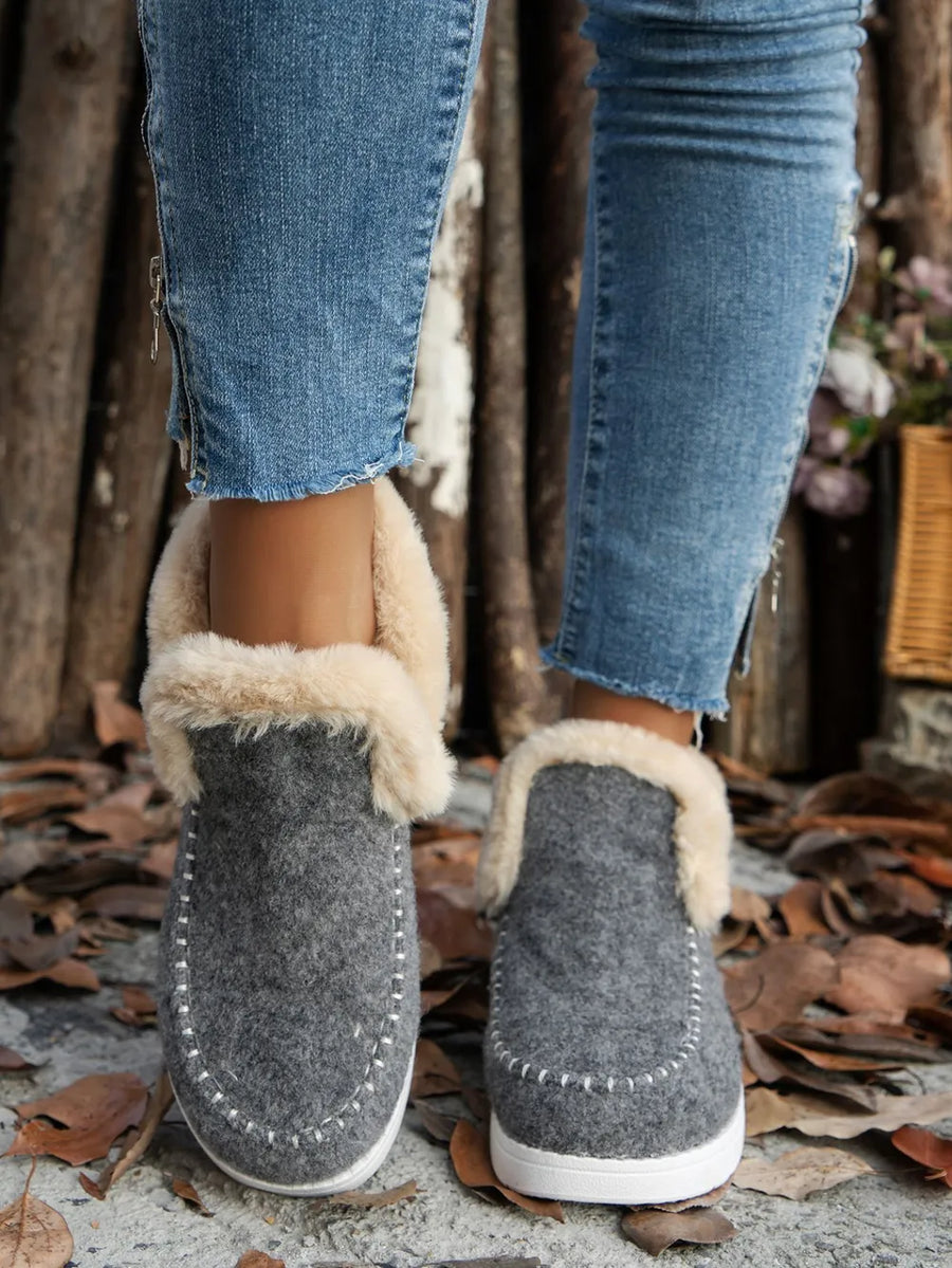 Gray felted slippers with faux shearling lining and white stitch detail.