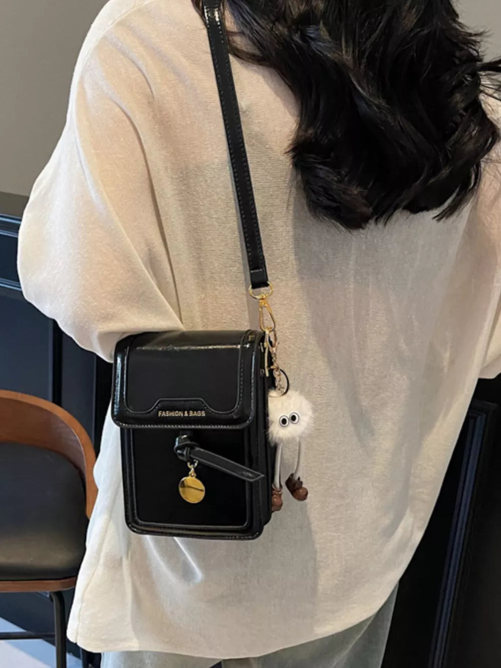 Sleek black pu leather mini crossbody bag with charm and fluffy keychain.