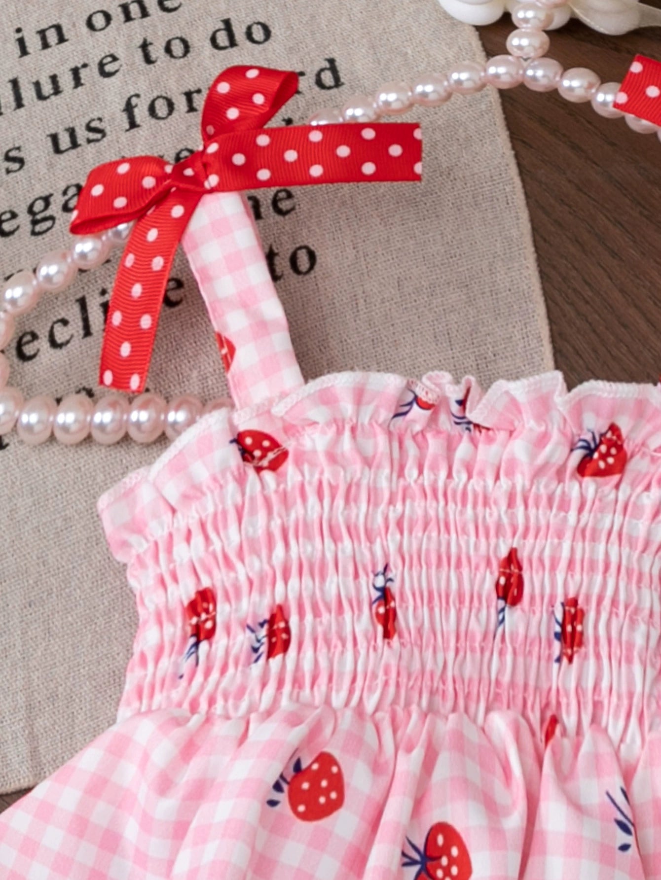 Pink smocked strawberry top with white gingham and red polka dot bows.