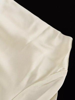 Cream satin dress with a subtle sheen and draped detail.