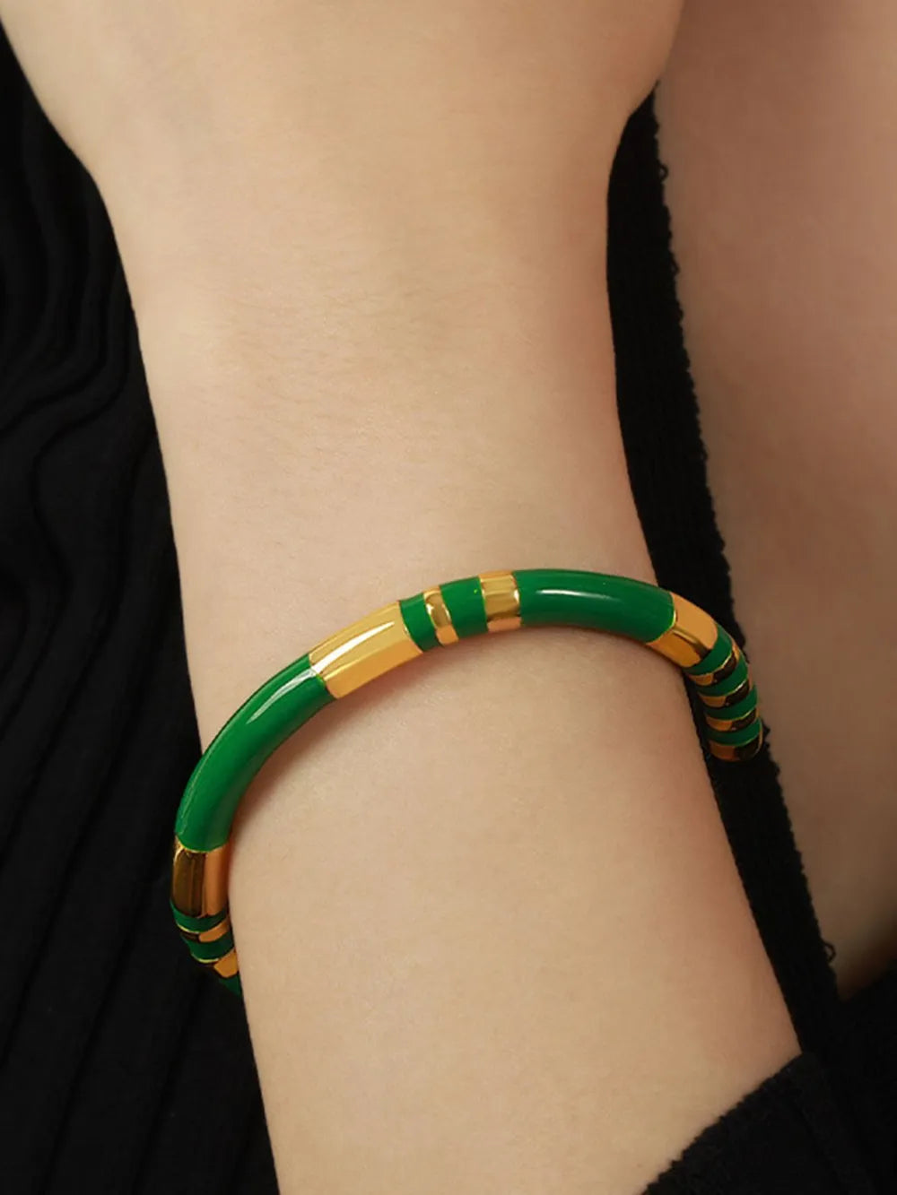 Striped enamel and gold bangle bracelet with dark green and gold accents.