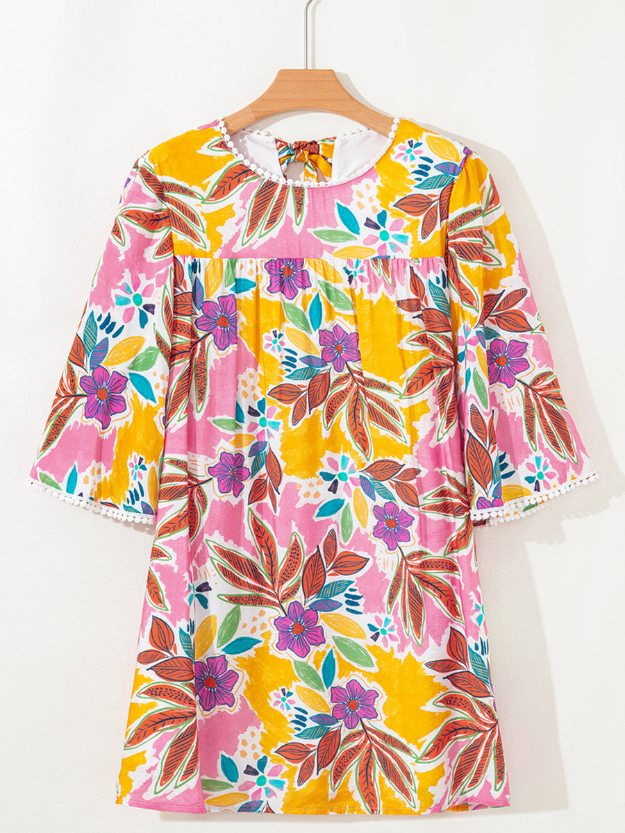 Print bell sleeve mini dress with colorful floral pattern and pom-pom trim.