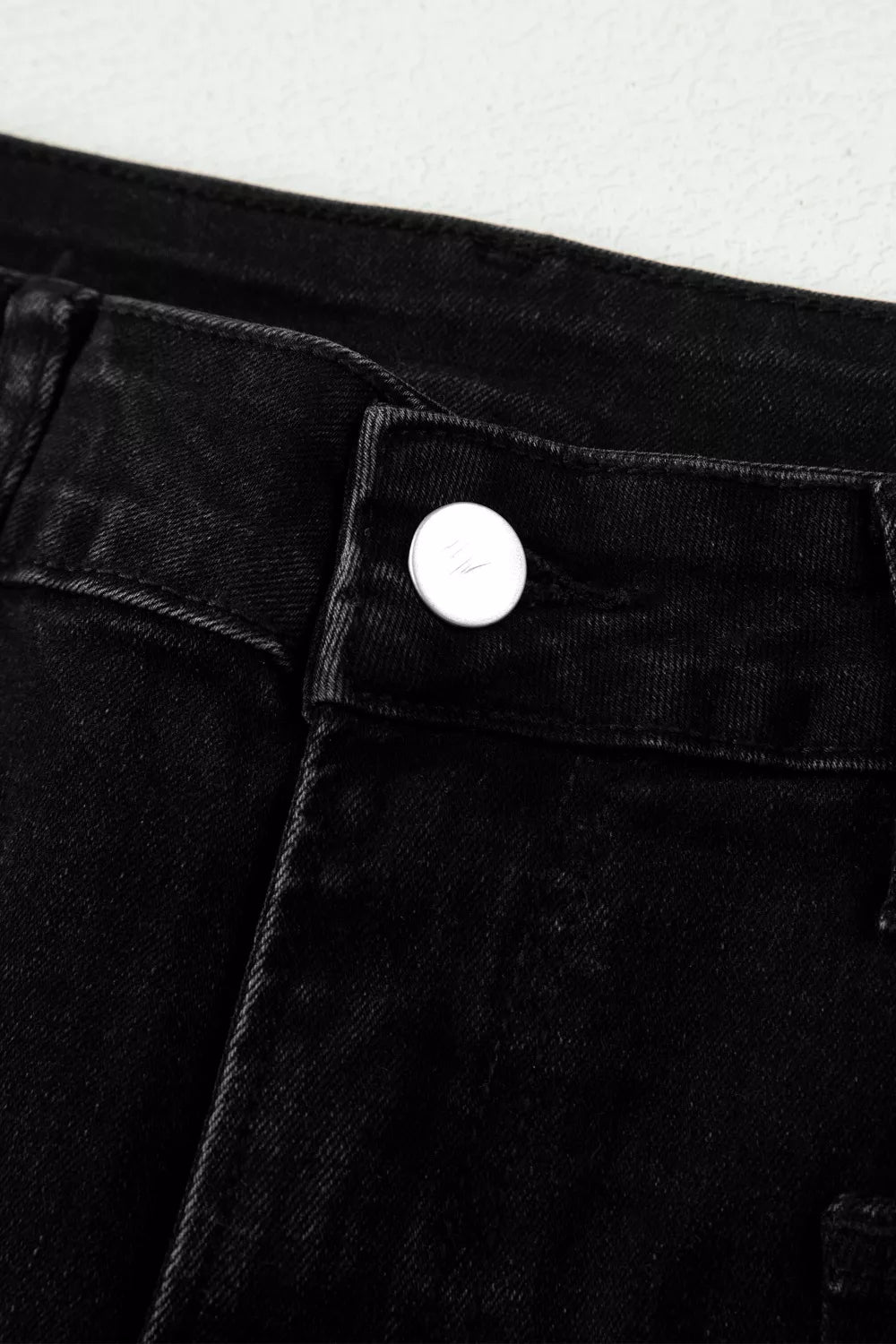 Black high-waisted cropped jeans with a button closure and raw hem detail.