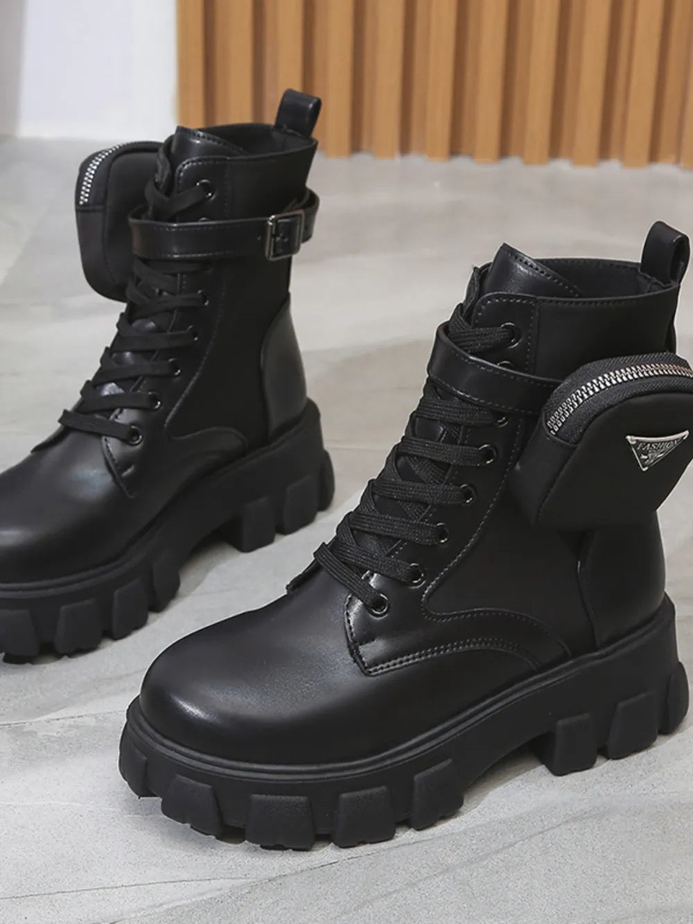 Black utility pocket lug sole boots with buckle detail and zipper pouch.