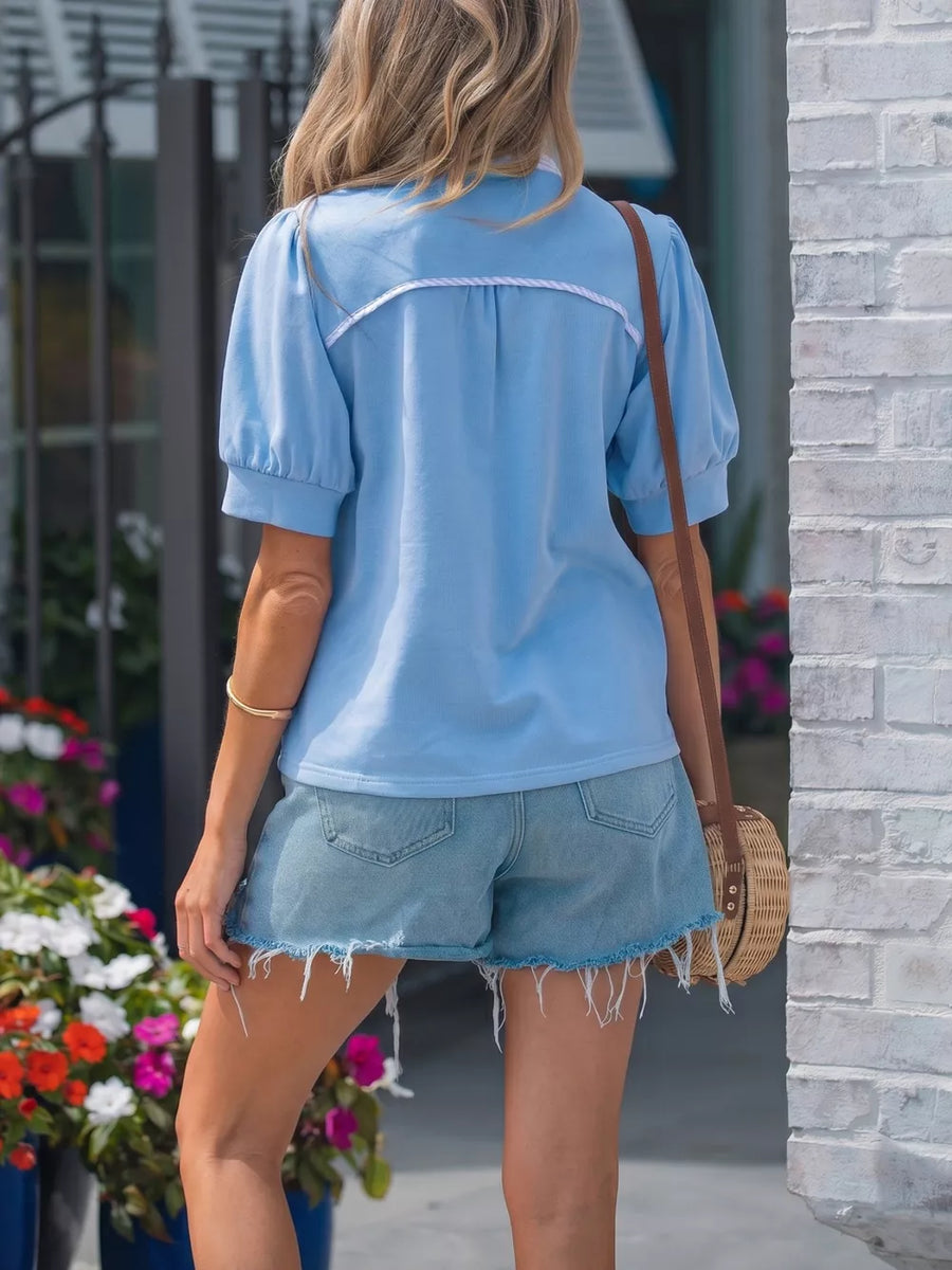 Light blue cotton maternity shirt with puff sleeves, collar, and white trim detail.