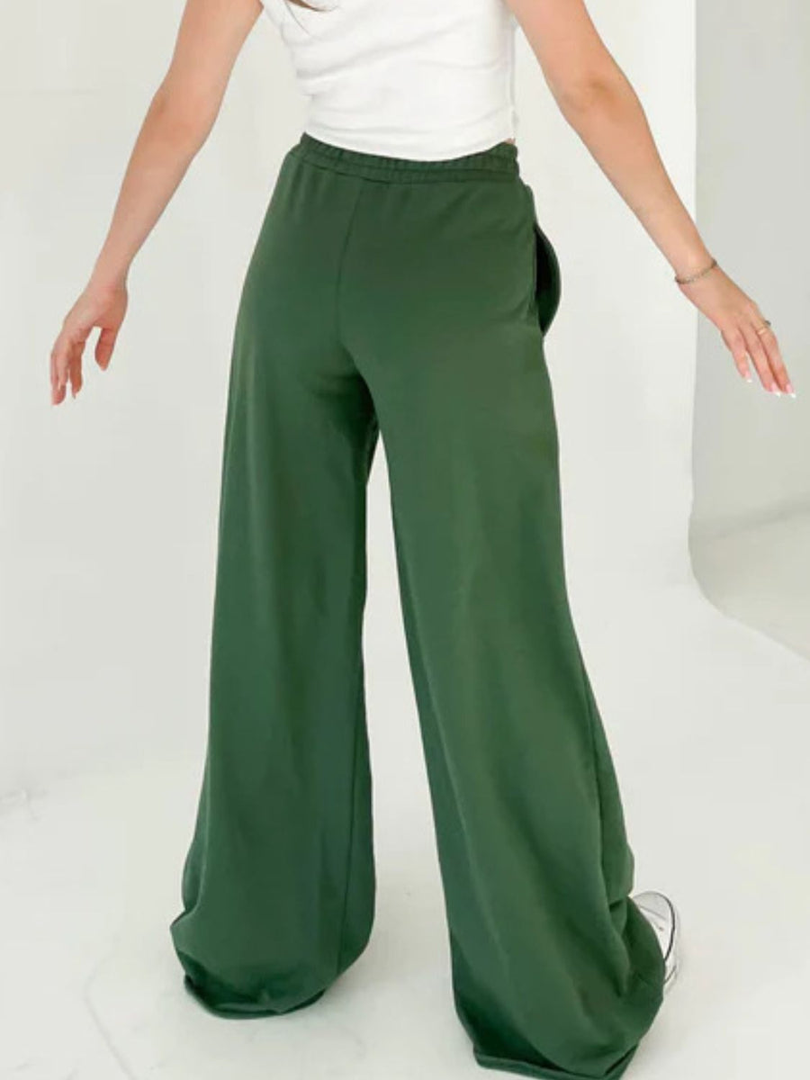 Dark green wide-leg lounge pants with pockets and a relaxed fit.