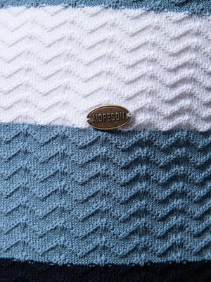 Chevron stripe knit polo shirt in white, blue, and dark navy with textured pattern and metal logo detail.