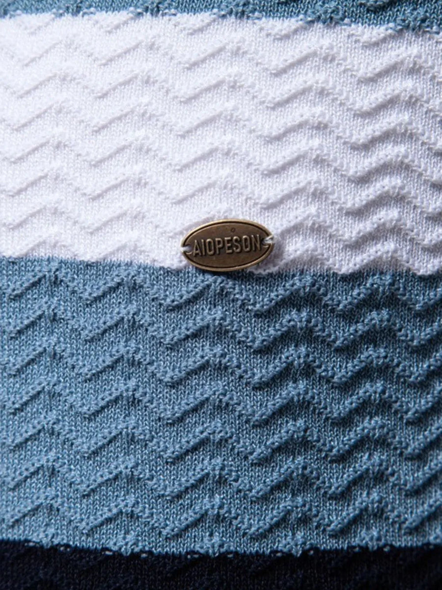 Chevron stripe knit polo shirt in white, blue, and dark navy with textured pattern and metal logo detail.