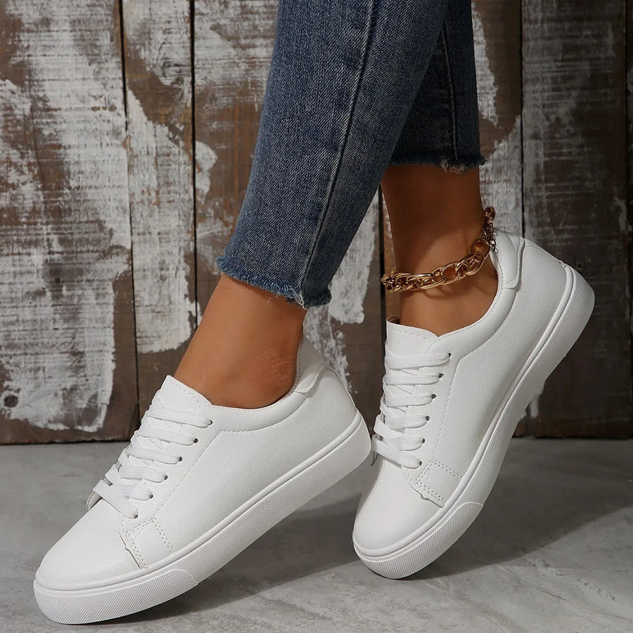 White leather-look platform sneakers with lace-up closure and gold chain ankle bracelet.