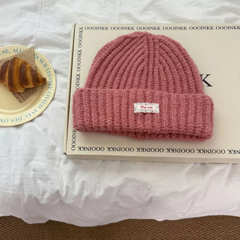 Pink chunky knit beanie with ribbed texture and decorative label