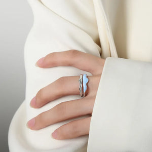 Sculpted enamel wave ring in light blue and silver on a finger.