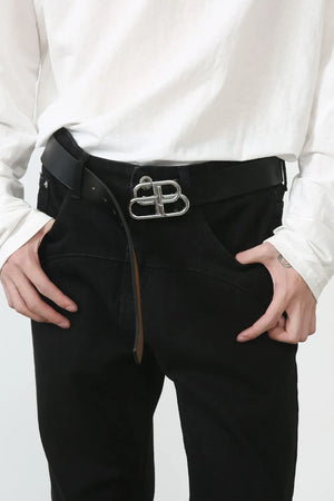 Black denim trousers with flared seam detail and silver buckle, styled casually.