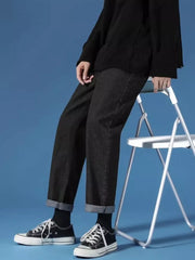 Black relaxed-fit straight-leg jeans with cuffed hems, styled with sneakers.