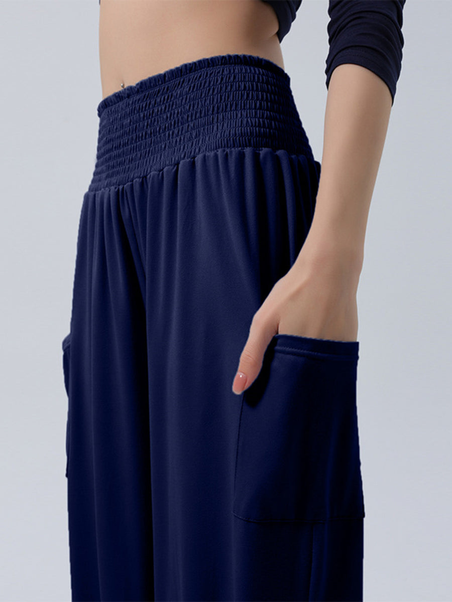 Blue smocked waist harem pants with pockets shown on a model.