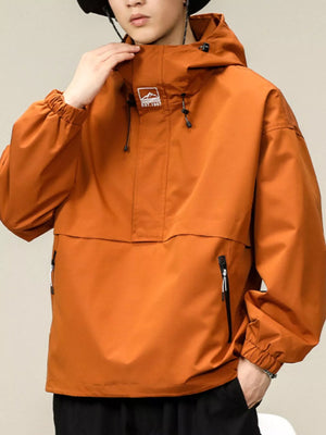 Orange oversized hooded windbreaker jacket with drawstring hood and zippered pockets.