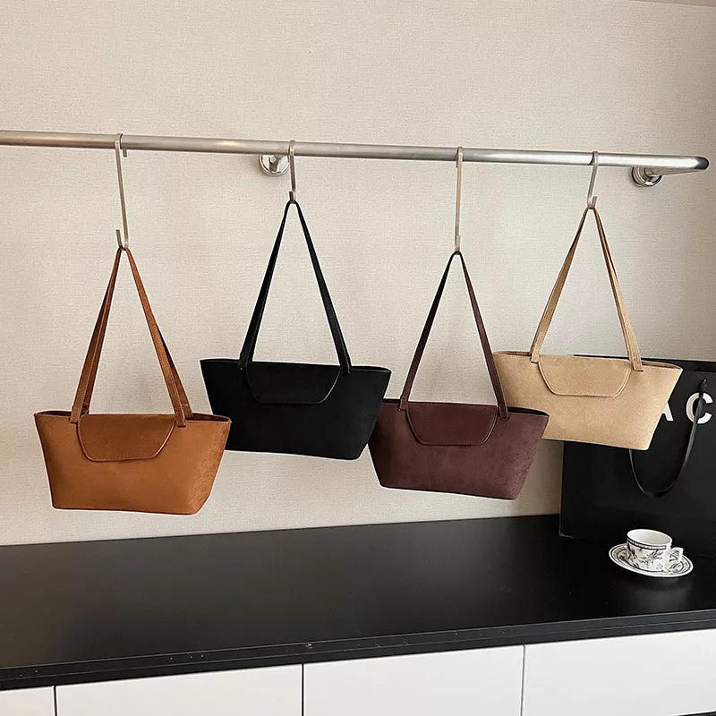 Suede flap tote bag in khaki, brown, black, and terracotta with shoulder straps.