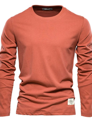 Coral crew-neck long sleeve tee with textured fabric and a logo patch detail.