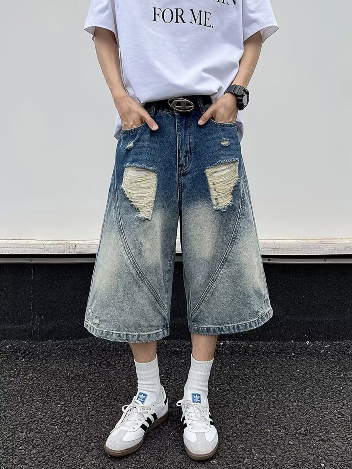 Men's distressed wide-leg denim shorts in blue with ripped details and a faded wash.