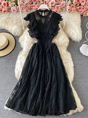 Black lace maxi dress with ruffles, cutout waist, and high neckline.