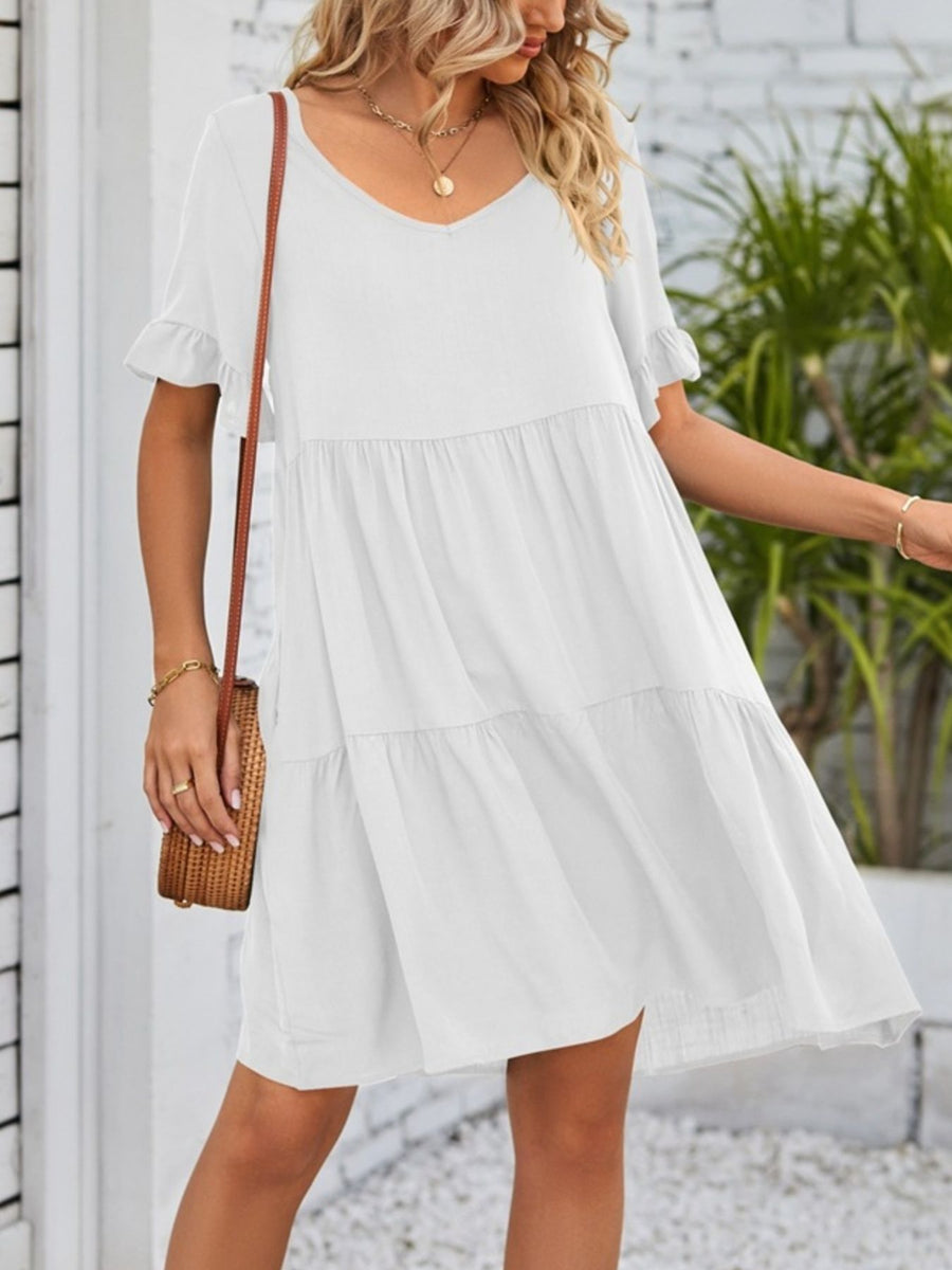 White tiered mini dress with ruffled short sleeves and V-neck.