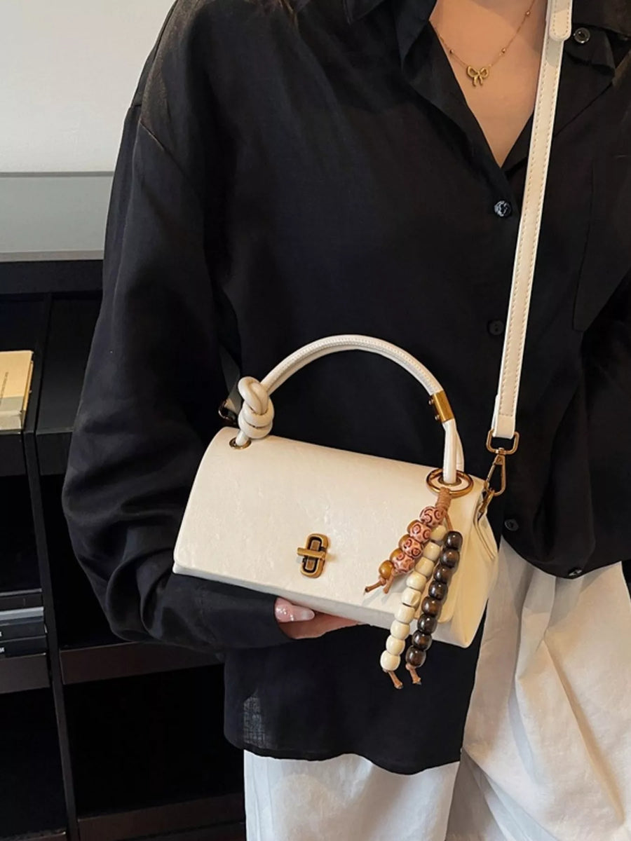 Ivory leather crossbody bag with knotted handle and beaded charm detail