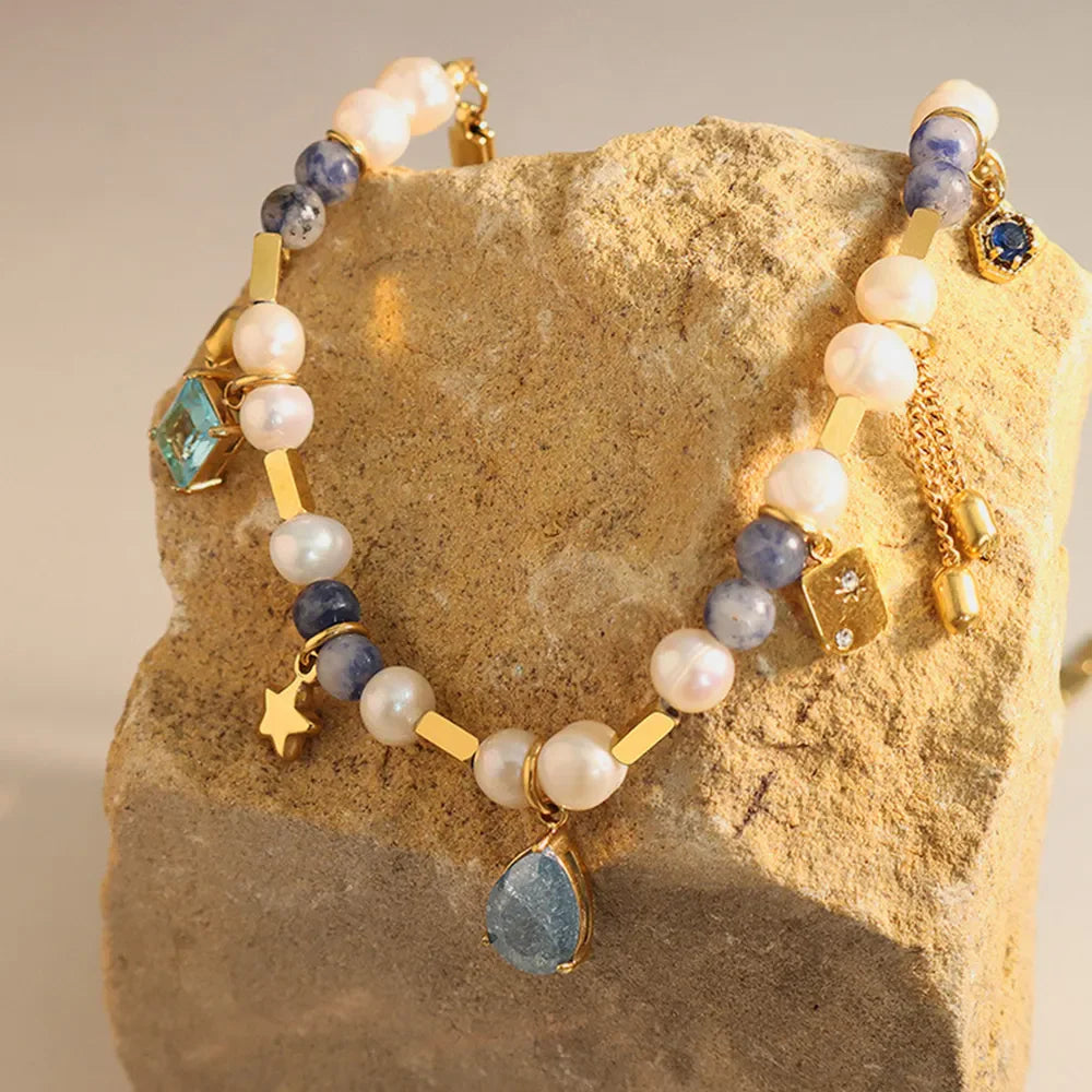 Gold celestial charm necklace with pearls, blue stones, star and teardrop pendant.
