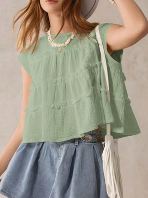 Green tiered ruffle blouse with short sleeves and a relaxed fit, styled with a denim skirt.