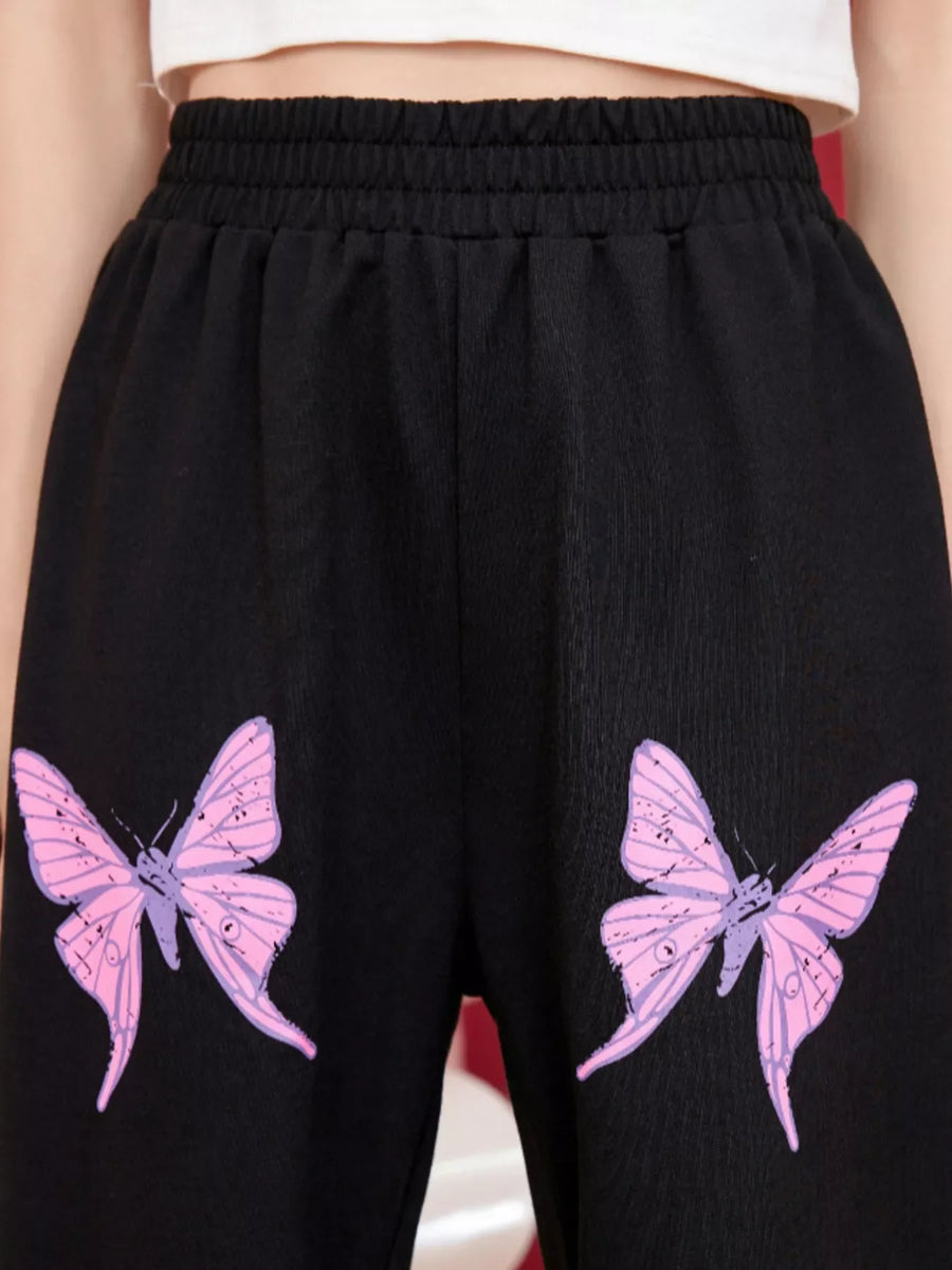 Black sweatpants with pink butterfly embellishments and an elastic waistband.