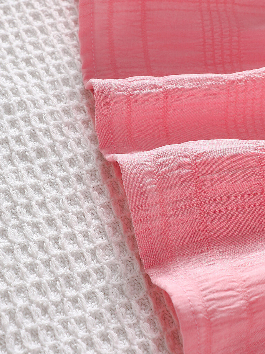 Pink baby top with subtle plaid texture and ruffled trim detail
