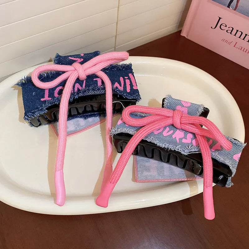 Denim patchwork claw clip with pink drawcord and text detail.