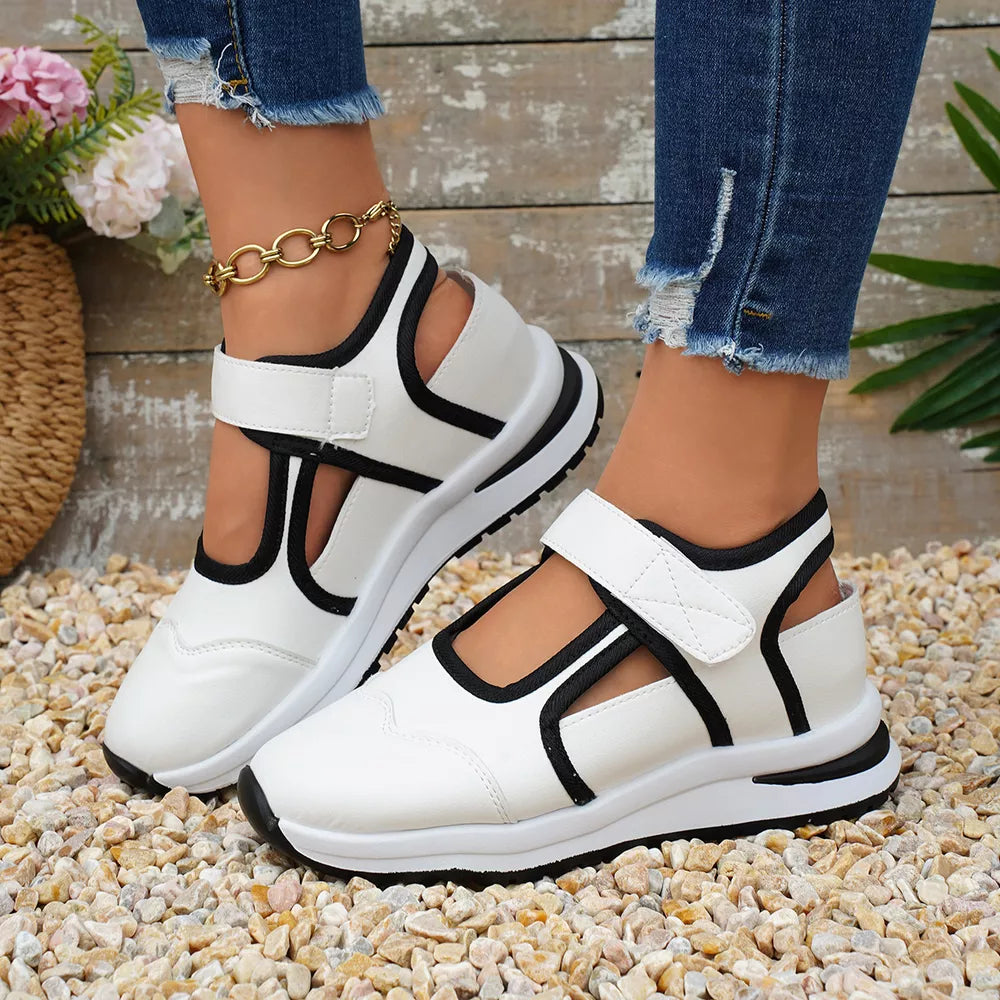 White Mary Jane cutout sneakers with black contrast trim and velcro straps.