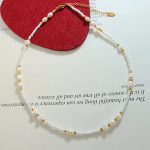 White seed bead and pearl strand necklace with gold accents
