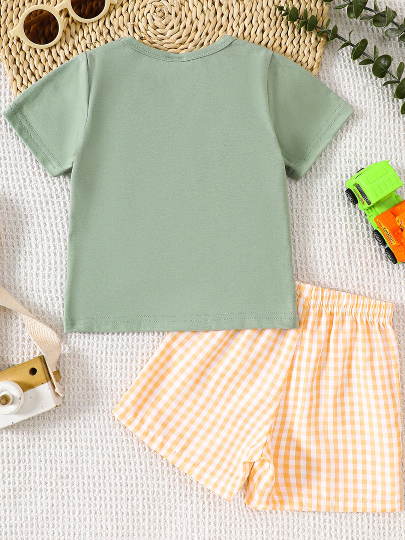 Light green cotton baby tee with embroidered tractor and yellow gingham shorts.