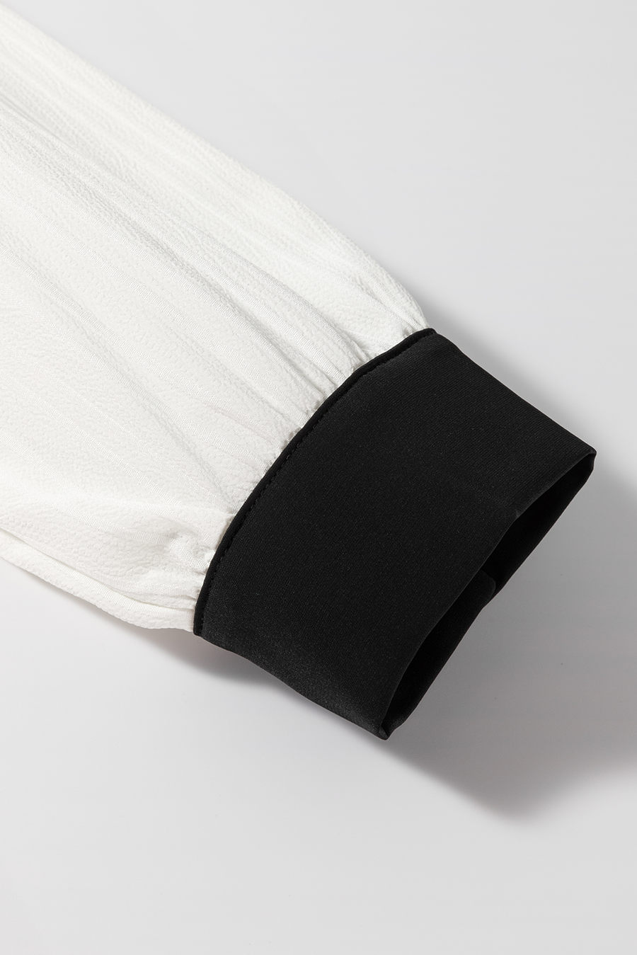 White textured blouse sleeve with black trim cuff