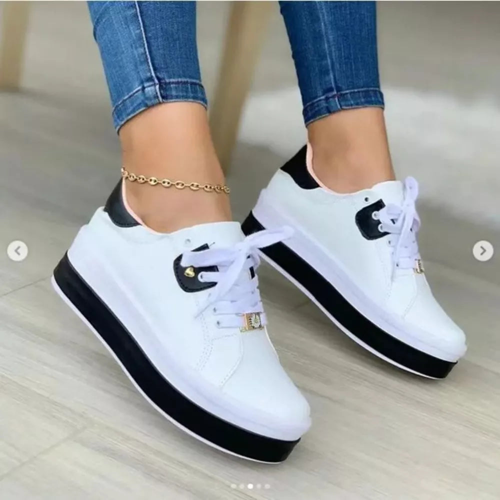 White lace-up platform sneakers with black accents and a gold ankle bracelet.
