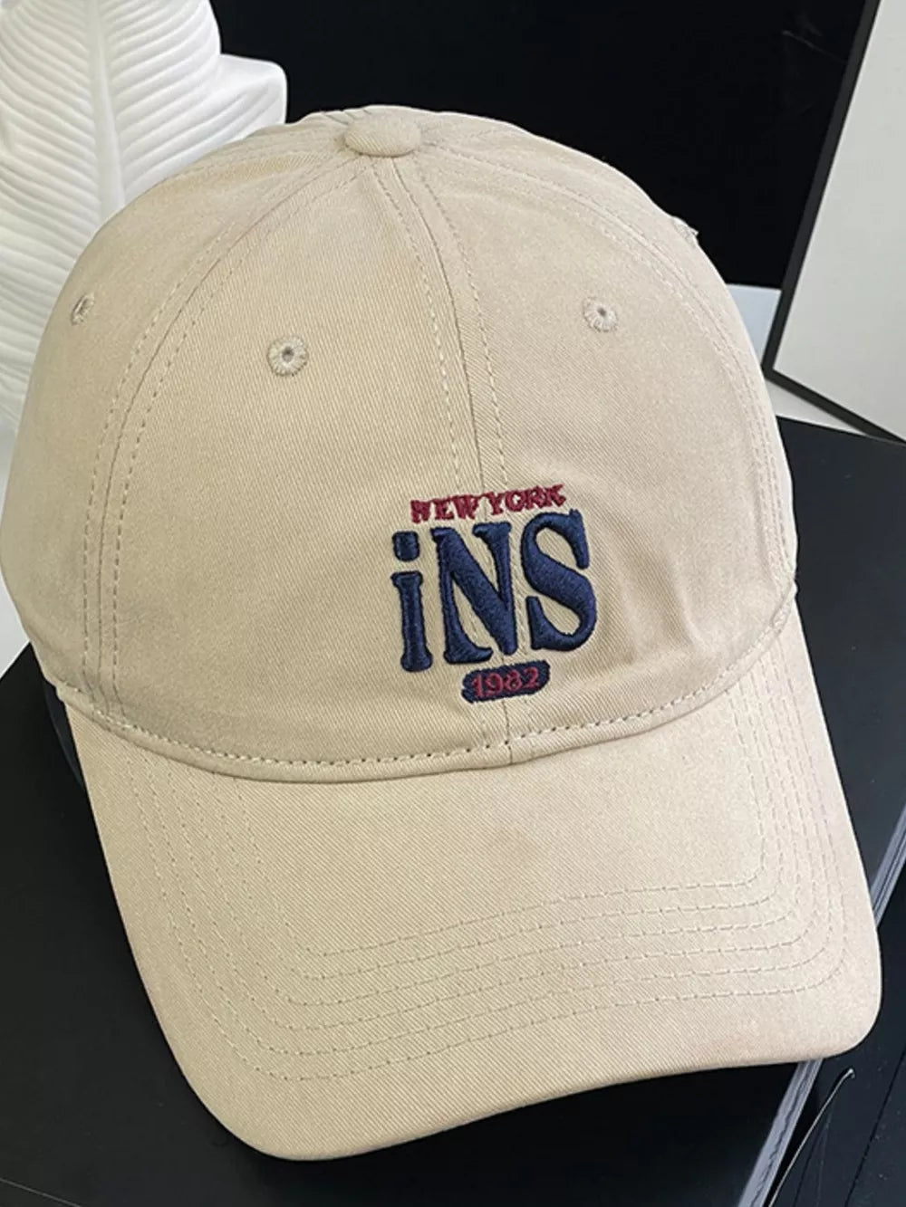 Tan baseball cap with embroidered New York INS 1982 logo