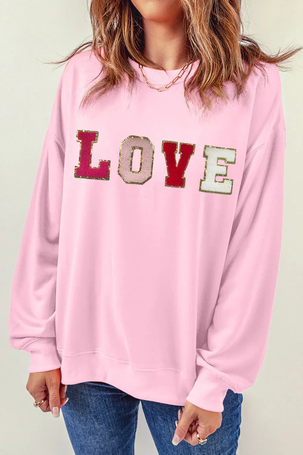 Blush pink sweatshirt with embellished LOVE lettering and gold trim.
