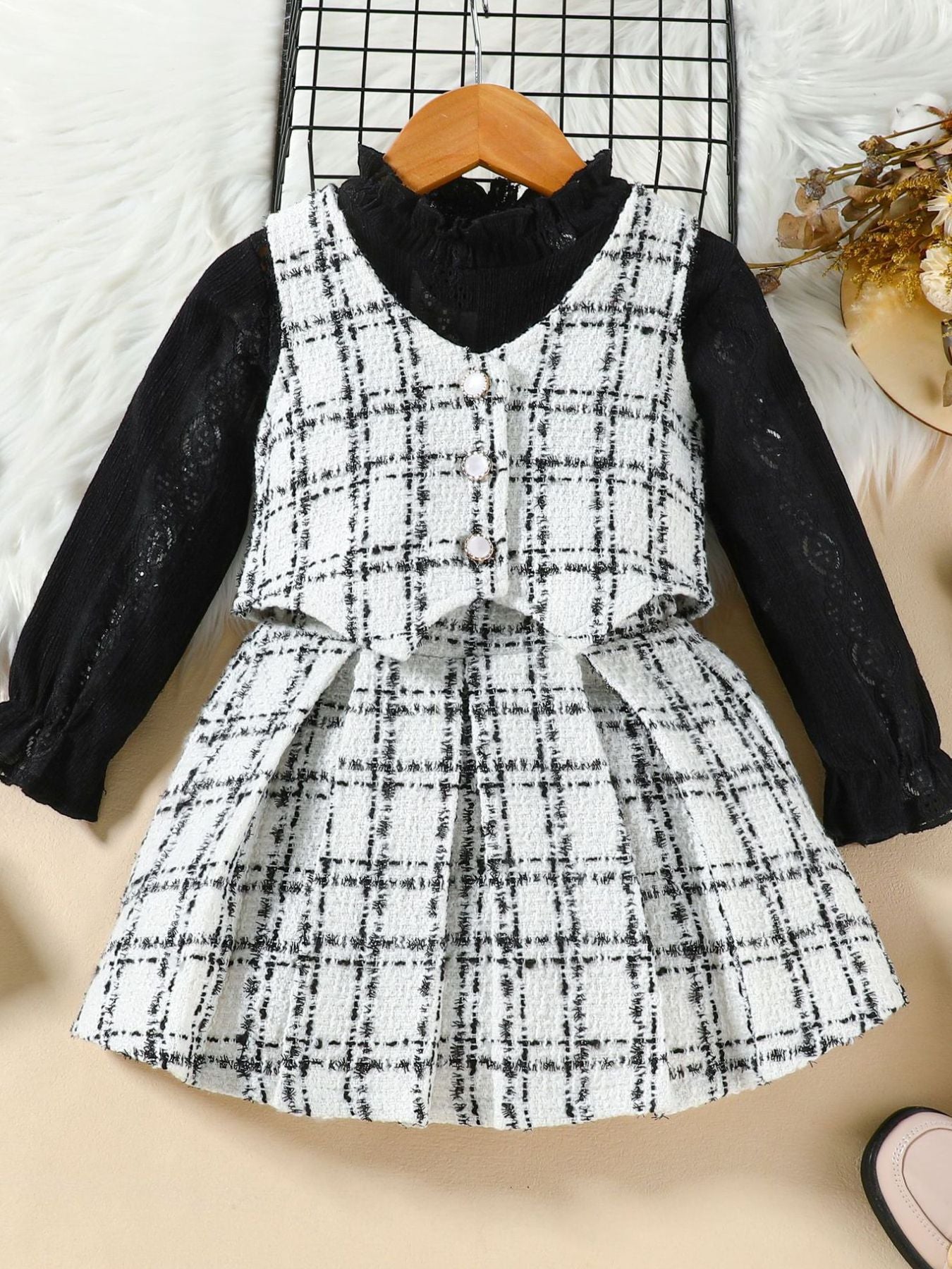 Toddler black long sleeve top with white plaid vest and skirt set with decorative buttons.