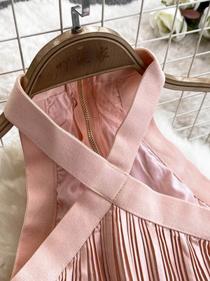 Pink pleated maxi dress with cutout detail and crisscross straps.