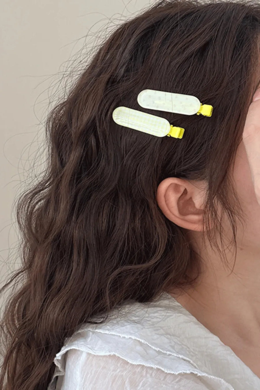Pastel yellow plaid hair clips with yellow clasps in wavy brown hair