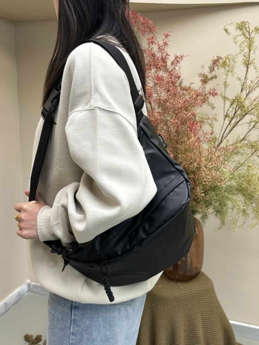 Black nylon crossbody bag with adjustable strap and zipper details