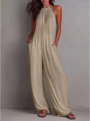 Khaki wide-leg jumpsuit with halter neck and textured fabric, featuring pockets.