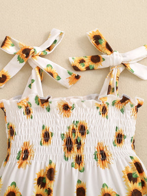 Baby jumpsuit with sunflower print, smocked bodice, and tie straps.