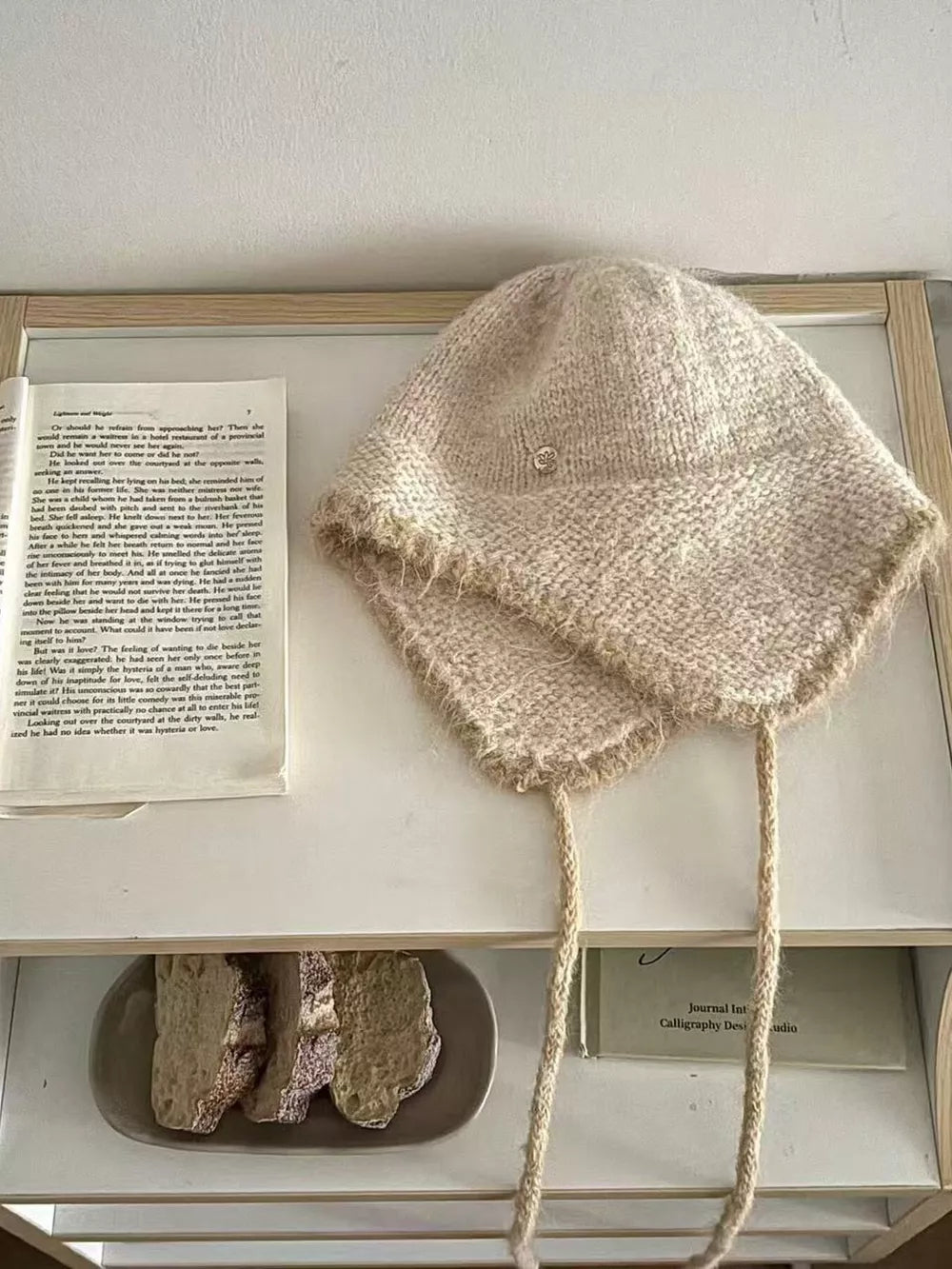Wool-blend hat with ear flaps in ivory, featuring braided ties and contrast trim.
